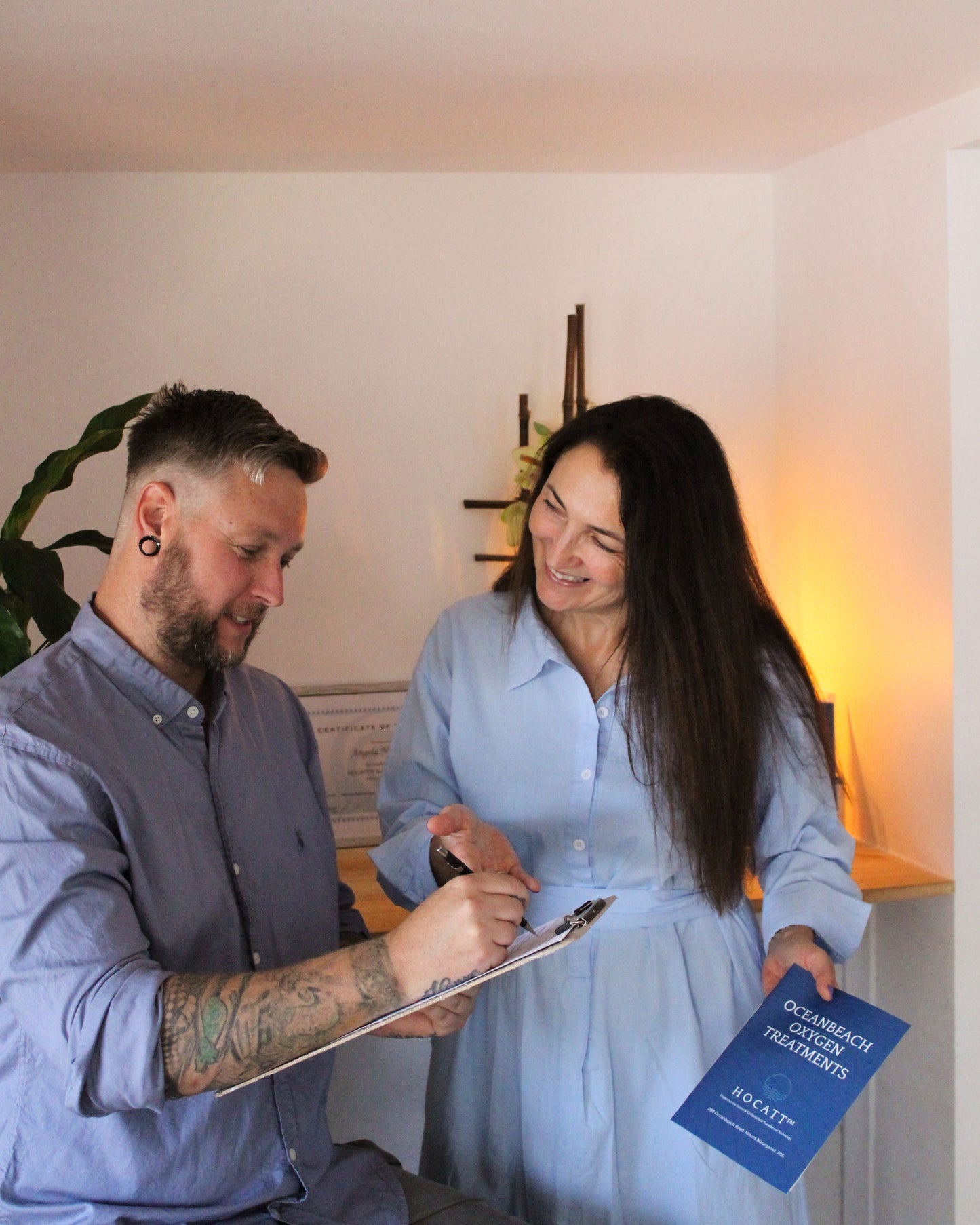 A client receives a free consultation for Oceanbeach Oxygen treatments, discussing HOCATT sauna and PEMF therapy options with a knowledgeable practitioner.
