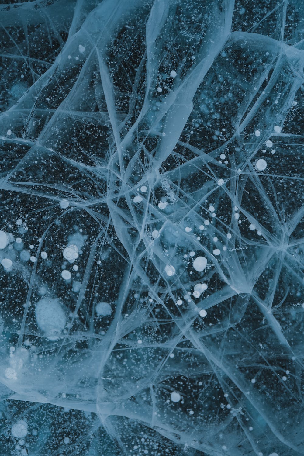Abstract image of fractured ice with embedded bubbles, visually representing the deep cellular activation and rejuvenation provided by PEMF therapy at Oceanbeach Oxygen in Mount Maunganui.