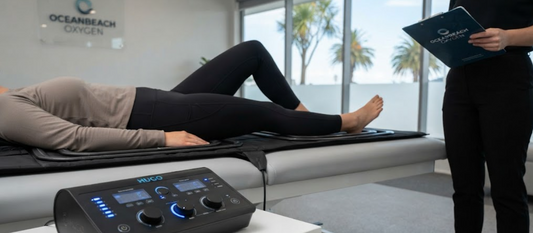 Generic view of a client receiving high-intensity HUGO PEMF therapy on a mat system in the Oceanbeach Oxygen clinic, Mount Maunganui, New Zealand, with the control unit visible.