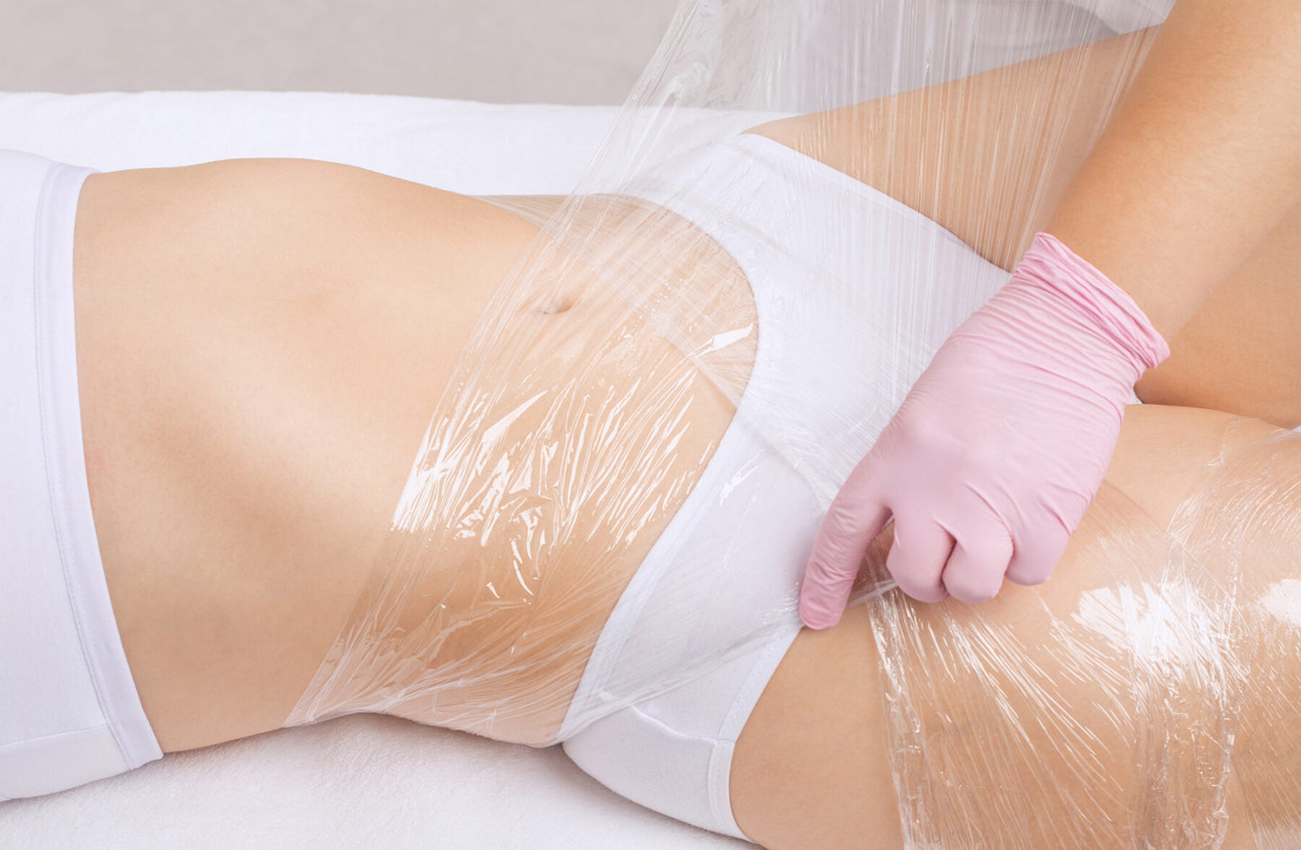 A close-up of a client receiving a body contouring slim wrap treatment at Oceanbeach Oxygen, showing a therapist applying the specialised wrap.