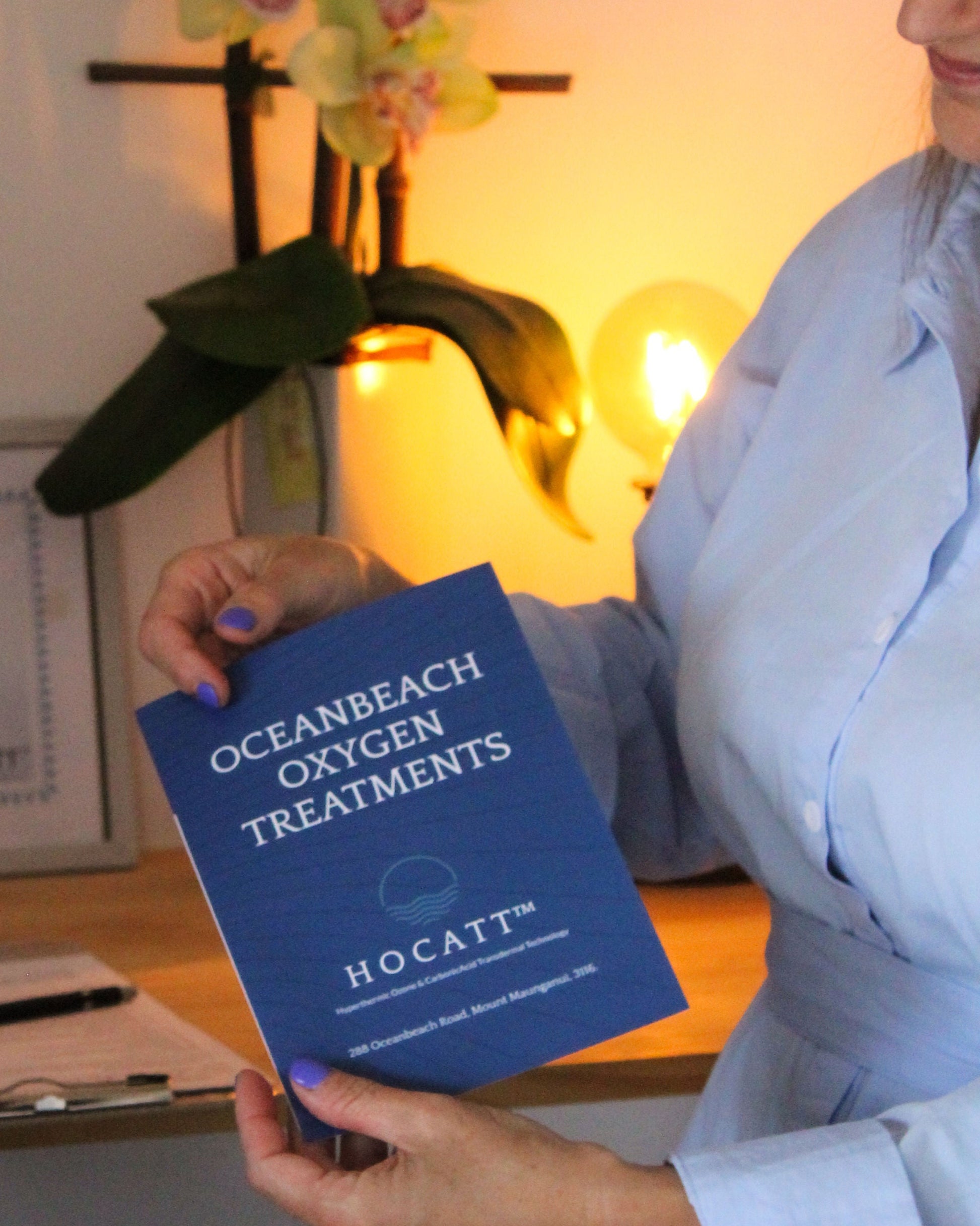 A practitioner at Oceanbeach Oxygen holds a branded brochure detailing the benefits of HOCATT™ treatments, perfect for a client consultation.