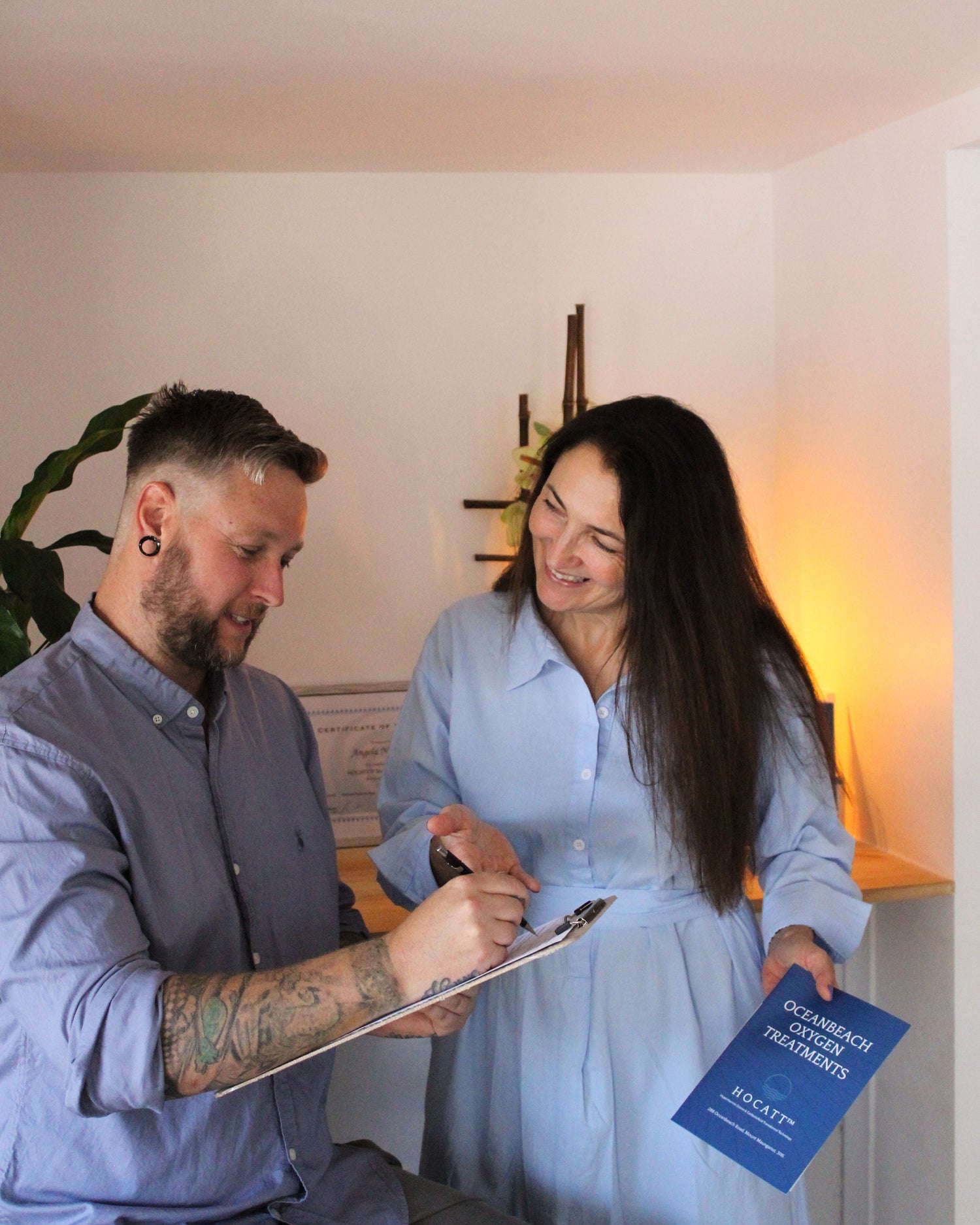 A client receives a free consultation for Oceanbeach Oxygen treatments, discussing HOCATT sauna and PEMF therapy options with a knowledgeable practitioner.